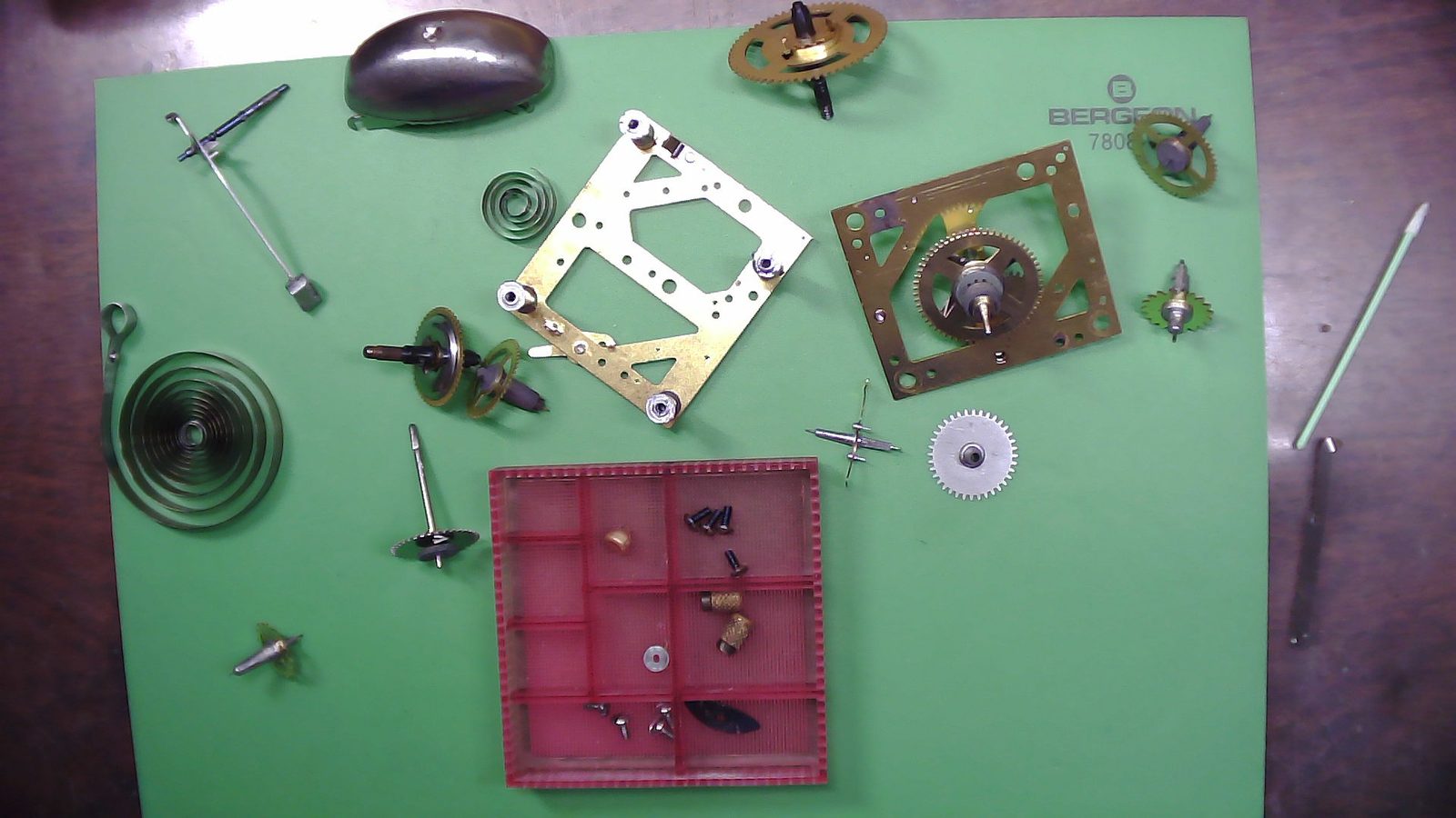 Taken Apart — So this is the pile of parts from the Raven Dismantle. The alarm spring is broken, but I don't know where the part that broke off is. Also, apparently I did not photograph the breakdown of this clock very well, so I'm going to have this research about how it goes back together. There's not a ton of parts in this clock, and it's simple by design because there's a wartime clock where brass, in particular, was being rationed. So one of the things about this clock is there's a lot less brass in it than most clocks of its time. The plates are very thin. A lot of the parts are mixture of steel and brass instead of all brass. And I'm also missing the winding knob for, I think it was the time, the abuse of the alarm. Whatever the case, I'm missing that knob and I can't find it, so I'm not going to look around my drawer and see what I've got.